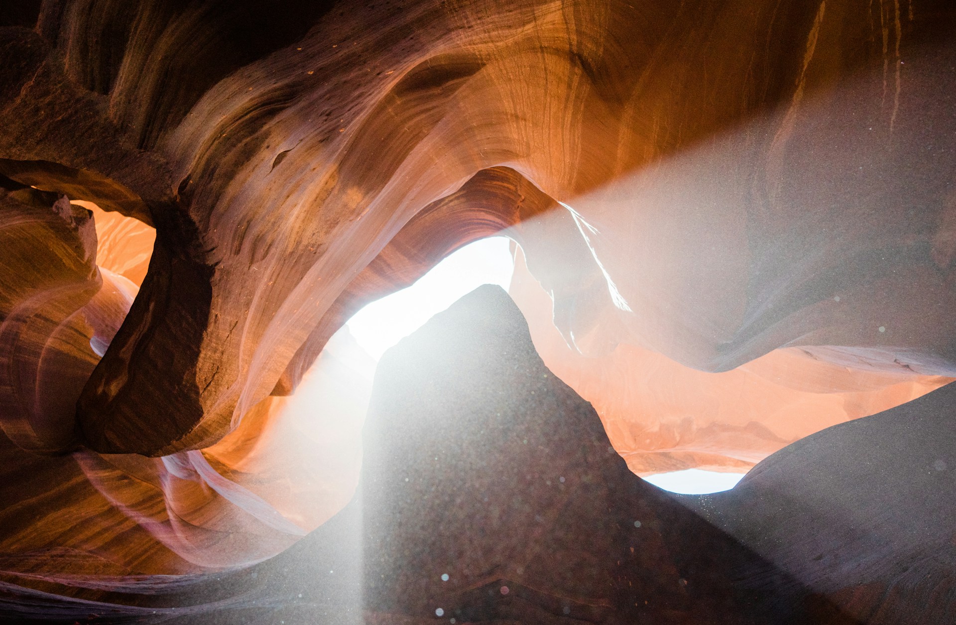 Intense sunlight streams through the cracks at the top of antelope canyon